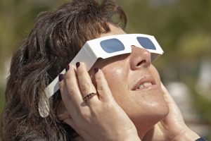 Woman with solar glasses looking at sun